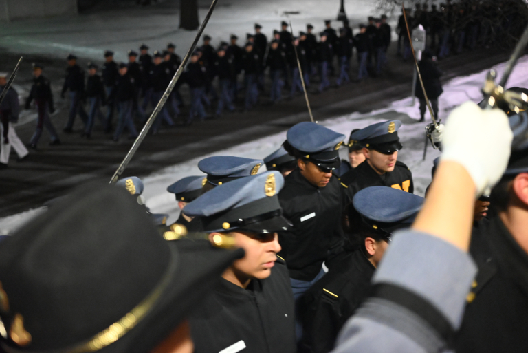 A close-up of cadets walking in file into a building.