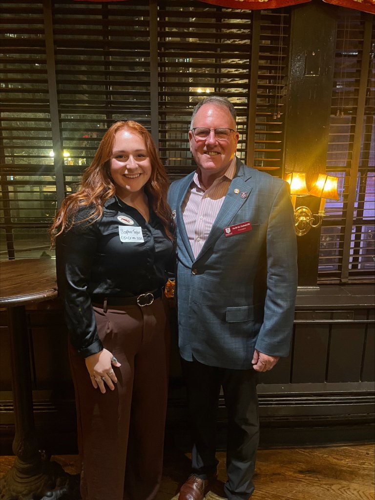 A woman and man stand next to each other in formal dress.