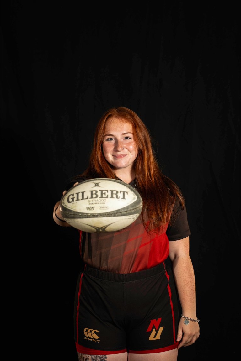 A women's ruby player poses with a ball for a portrait.