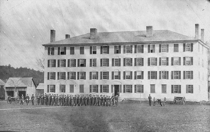 Old Norwich campus building with students gathered in the distance