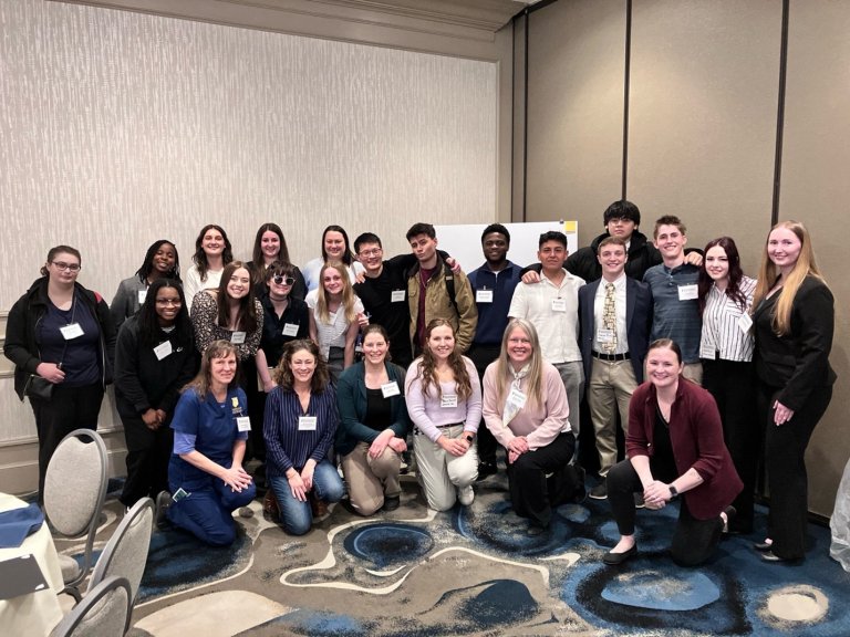 Group of students and staff pose together in a conference room.