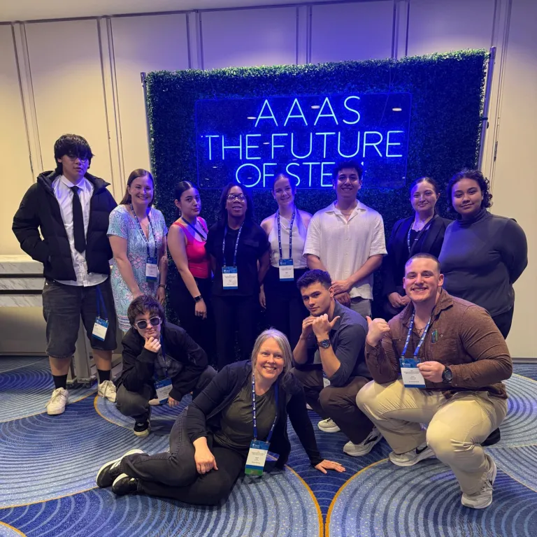 Group of students and staff pose in front of an AAAS The Future of STEM sign.