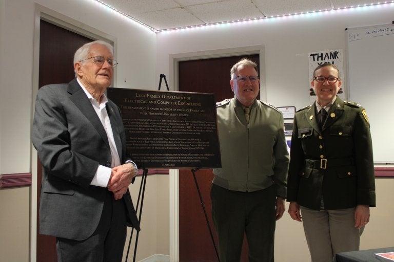 Three people stand beside a plaque for the Luce Family Department of Electrical and Computer Engineering.