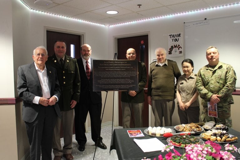 Seven people stand beside a plaque for the Luce Family Department of Electrical and Computer Engineering.