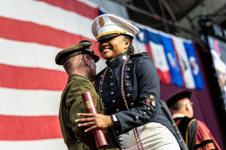 Cadet in dress uniform receives diploma during Norwich University graduation ceremony.