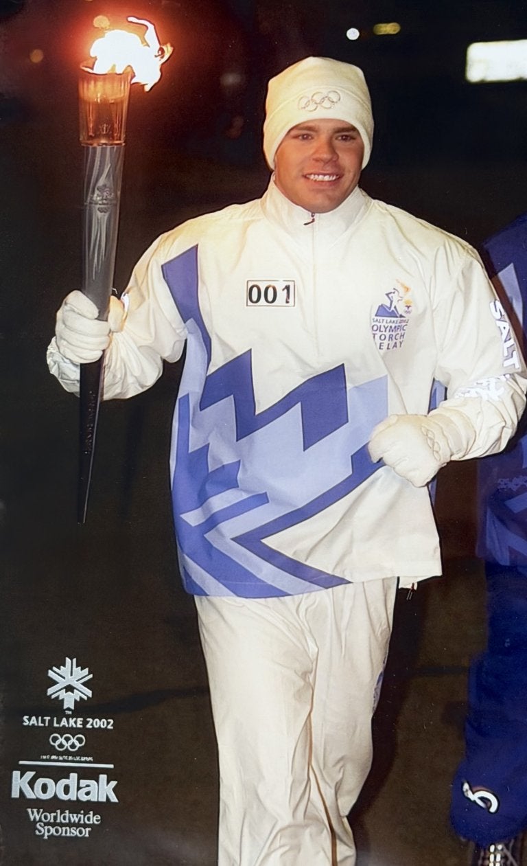 Torchbearer carries the Olympic torch during the Salt Lake 2002 Olympic Torch Relay wearing a white relay uniform.