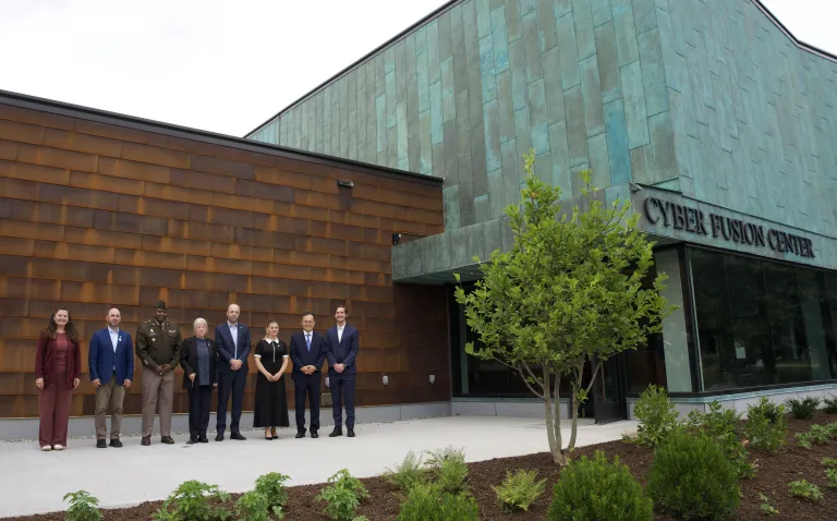 Seven people stand outside the Cyber Fusion Center.