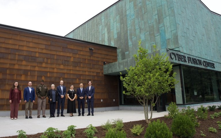 Seven people stand outside the Cyber Fusion Center.