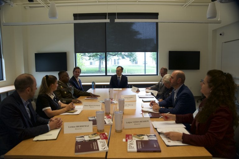 People sit around a conference table with notebooks and name cards.