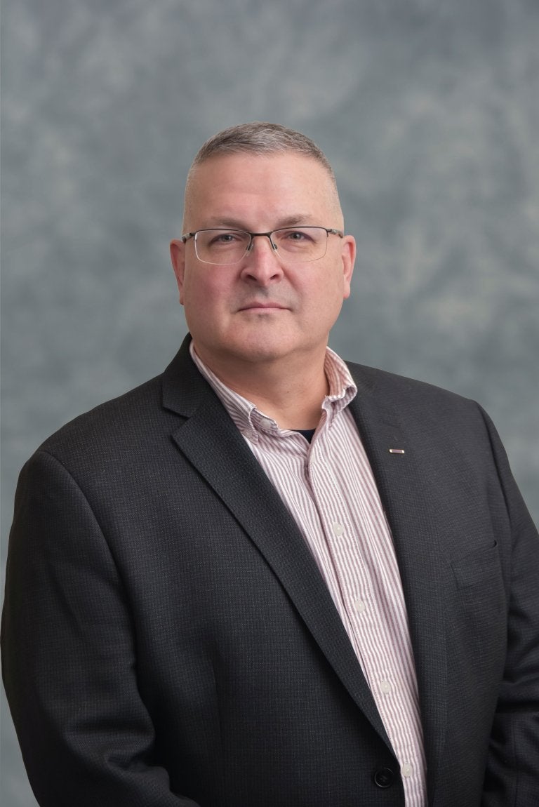 Portrait of a man in a collared shirt and jacket on a grey background