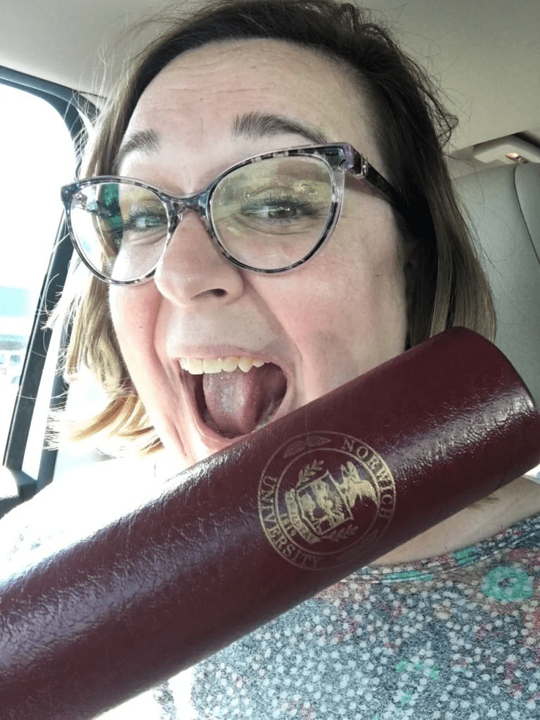 Shannon Murphy holds a Norwich University diploma case inside a vehicle.