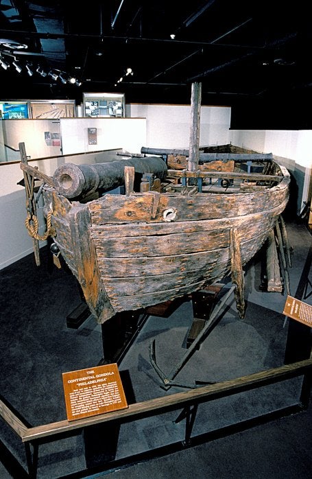 A wooden Continental Gondola with a cannon on display in a museum.