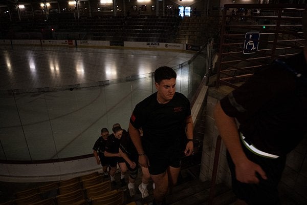 Students climb stadium steps beside an indoor ice rink.
