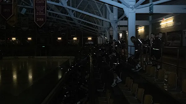 Students exercise on stadium steps in a dark indoor arena.