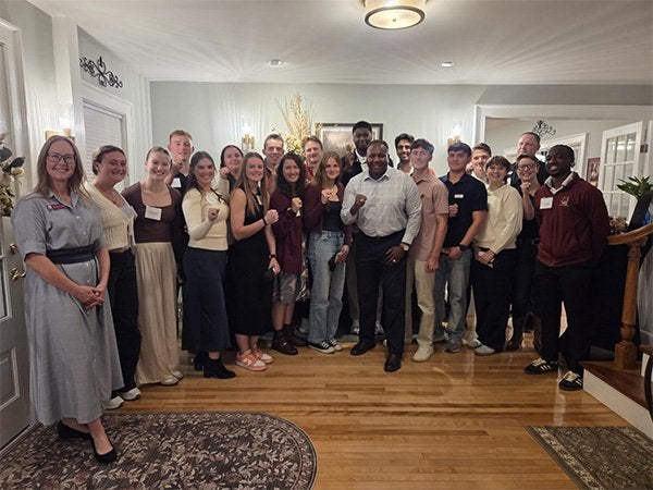 A group of people stands together indoors, with several holding small objects toward the camera.