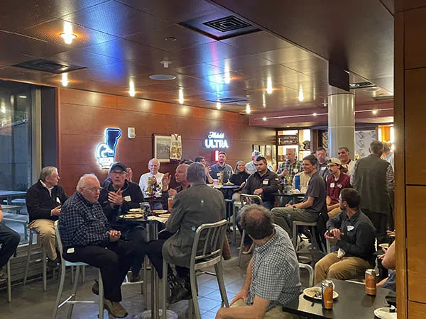 A group seated around tables in a restaurant applauds during a gathering.