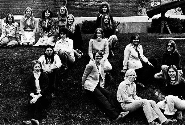 A group of people pose together on a grassy slope in a black-and-white photograph.