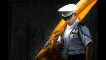 A member of the NU color guard walks through a last bit of sunlight as he leaves Sabine Field.