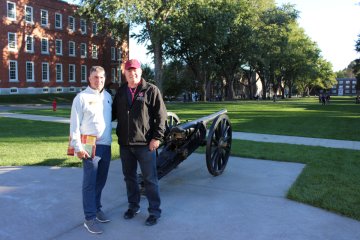 two alumni before the Upper Parade ground cannon, at 2025 Homecoming Review with Retreat