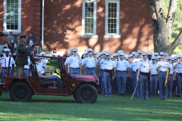 group in jeep with man standing at back, before cadtes, at 2025 Homecoming Review with Retreat