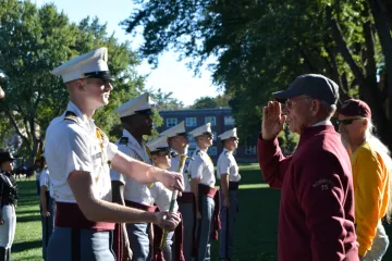 alumnus saluting a cadet holding a sabre, at 2025 Homecoming Review with Retreat