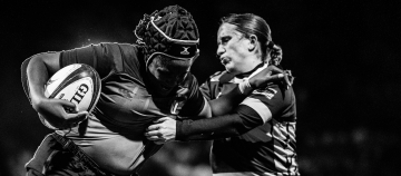 Two rugby players engaging intensely during a night game.