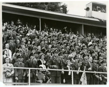 Norwich University cadets and other spectators in the bleachers watching a football game in approximately 1962-1965