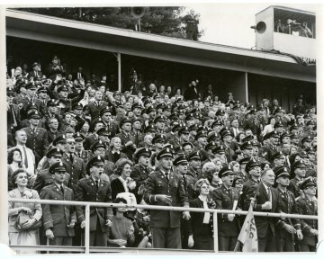 Norwich University cadets and other spectators in the bleachers watching a football game in approximately 1962-1965