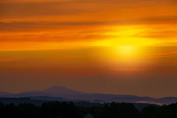 Sunset over a mountainous landscape with vibrant orange and red skies.