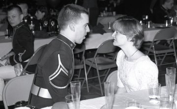 man in uniform looking at woman, sitting at a table