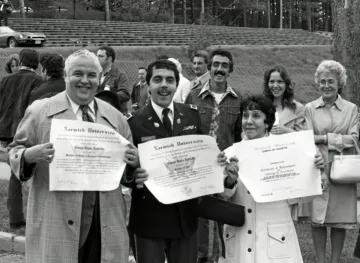 older man, younger man in uniform, woman holding diplomas