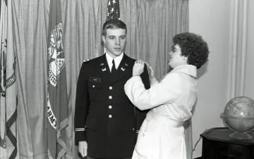 woman placing hands on shoulder of man in military uniform