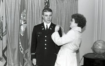 woman placing hands on shoulder of man in military uniform