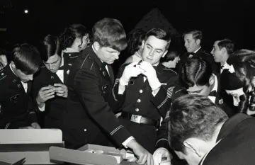 two cadets in uniform look at rings on table and in hand