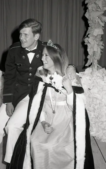 woman in formal dress and tiara with man in uniform