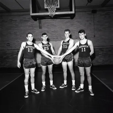four basketball players in basketball uniform, collectively holding a basketball
