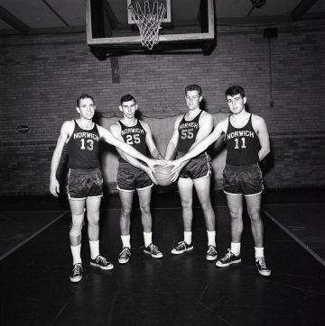 four basketball players in basketball uniform, collectively holding a basketball