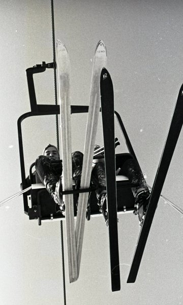 two skiers seen from below on a chair lift