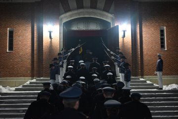 Rooks walk under an archway of swords into Plumly Armory.