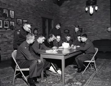 group of cadets, and professor, standing and sitting around a table