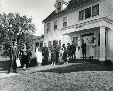 large group of men in military uniform, women in dresses, in front of entrance to building named "Roberts Hall"