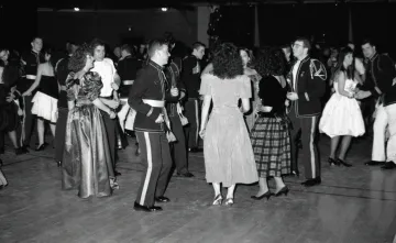 couple in foreground, cadet in uniform with woman from behind in dress, dance in front of a group of other couples
