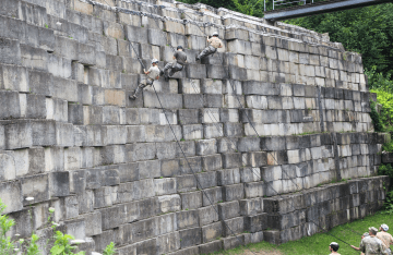 FLC demonstration of rappelling from large cement wall outside.