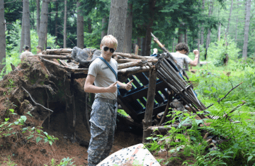 FLC attendee giving thumbs up after completing his shelter in the woods.