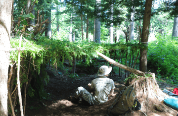FLC camper siting inside his forest shelter.