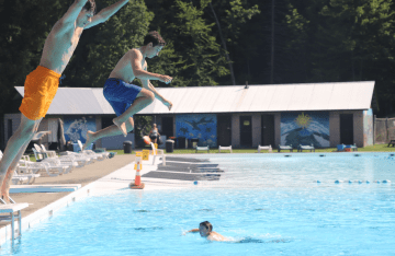 FLC campers jumping off the diving board into the swimming pool