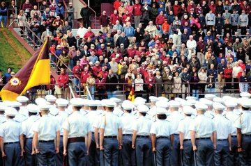 a group of Norwich cadets in formal uniform face a crowd of people in football stand. Photo from Norwich's 2010 Homecoming.