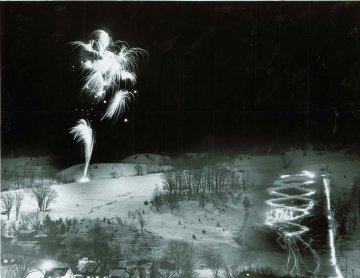 fireworks light up a dark sky above a snowy hill