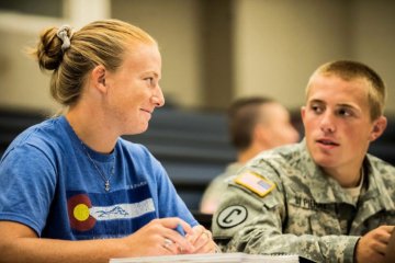 Two NU students looking at each other sitting in a study hall. At left is Hannah Bell '16.