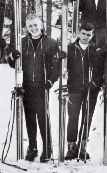 Two men in winter clothing stand holding their skis to their right: John D. Woods and Patrick J. Cunningham